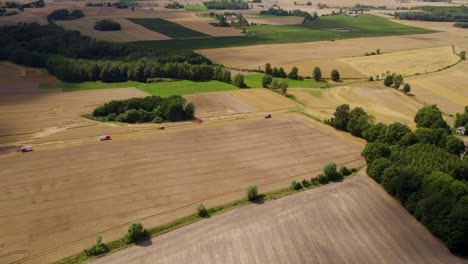 A-group-of-tractors-drive-through-farmlands,-harvesting,-farming