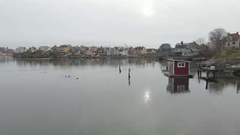 Eine-Nahe-Ansicht-Eines-Malerischen-Kleinen-Saunafloßes-Mit-Einer-Schwedischen-Flagge,-Die-Draußen-Hängt,-Stehend-Auf-Stillem-Wasser-In-Karlskrona,-Schweden-Mit-Ekholmen-Im-Hintergrund