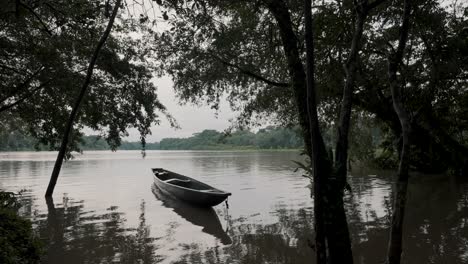 Wooden-Boat-Floating-In-The-Calm-Waters-Of-River-In-The-Amazonian-Rainforest-In-Ecuador