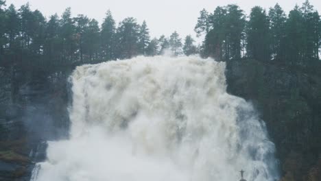 A-tiny-silhouette-of-a-person-under-the-huge-raging-Tvinderfossen-waterfall