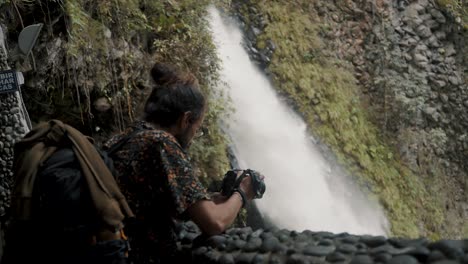 Männlicher-Reisender,-Der-Seine-Kamera-Nahe-Dem-Wasserfall-Pailon-Del-Diablo-In-Banos-De-Agua-Santa,-Ecuador-Betrachtet---Mittel