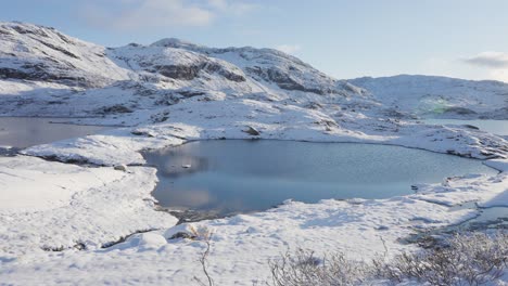 Two-small-lakes-connected-by-a-narrow-stream-in-the-snow-covered-northern-landscape