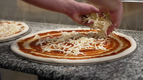 Chef-evenly-spreads-shredded-mozzarella-cheese-over-pizza