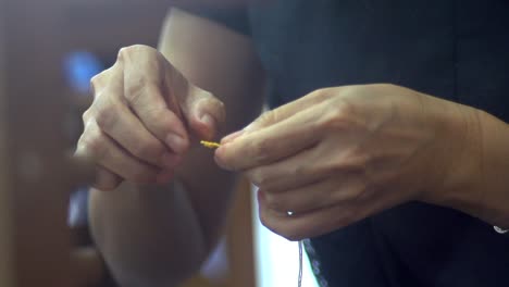 Tightening-of-knot-on-yellow-yarn-with-fingers