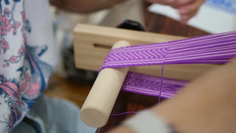 Purple-and-white-yarn-being-weaved-into-traditional