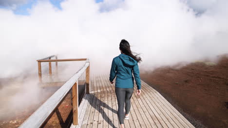 Young-woman-confidently-strides-towards-huge-clouds-of