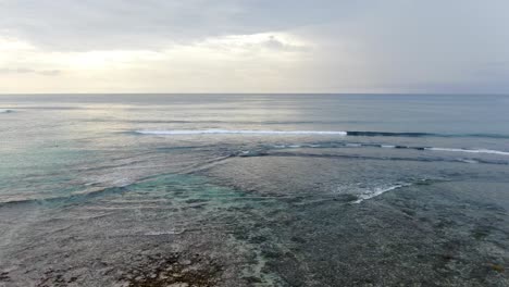 Ruhige-Wellen,-Die-Die-Küstenlinie-Der-Bali-insel-Bei-Bewölktem-Himmel-Treffen
