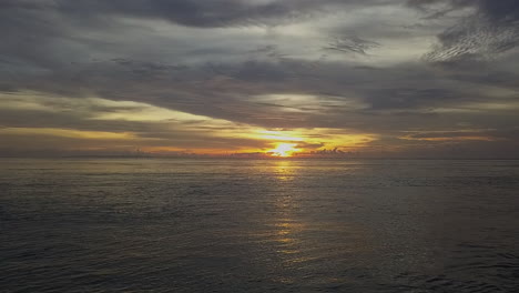 Dramatic-golden-sunset-cloud-sky-over-textured-ocean