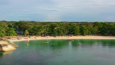 tourists-paddle-boarding-on-tropical-beach-at-Tanjung