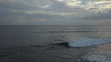 Surfers-ride-shore-break-wave-at-dusk-low