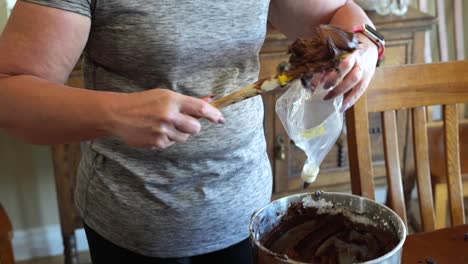 Scooping-chocolate-frosting-into-an-icing-bag-to