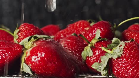 Kitchen-tap-water-splashing-onto-bright-red-strawberries
