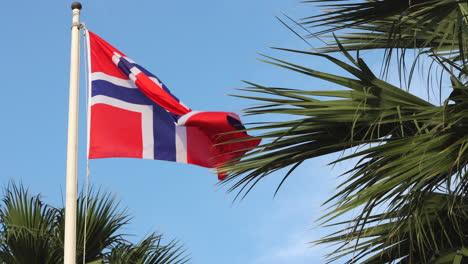 Norwegian-flag-blows-slowly-in-breeze-against-blue
