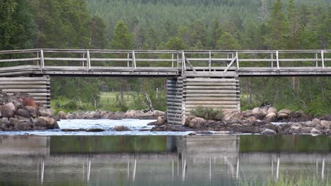 Old-wooden-log-bridge-over-small-river-One