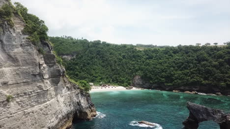 Cliff-aerial-reveals-tourism-huts-on-Atuh-Beach