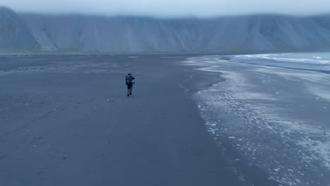 Drone-Fly-Over-Lone-Man-Walking-On-Stokksnes