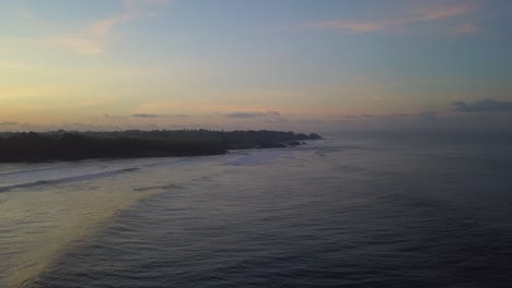 Pre-sunrise-dawn-aerial-as-ocean-waves-roll
