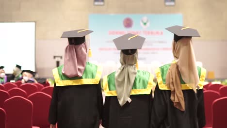 View-from-behind-three-female-graduates-walk-in