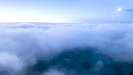 Plane-descending-through-thick-blue-clouds-at-blue
