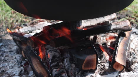 Wood-fire-burns-under-large-iron-kettle-cooking