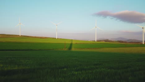 Flying-Above-Grassland-With-Wind-Turbines-Array-in