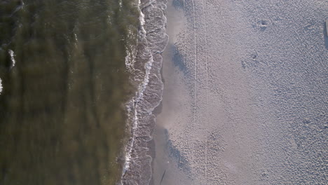 Aerial-top-down-shot-of-waves-reaching-sandy