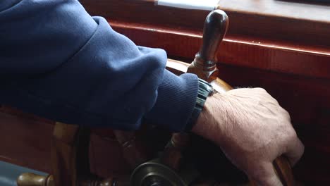 captain-with-old-hands-on-a-wooden-steering