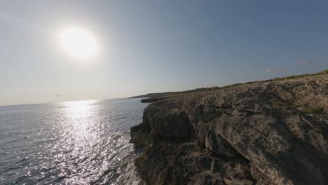 FPV-flight-along-rugged-limestone-ocean-cliffs-sun