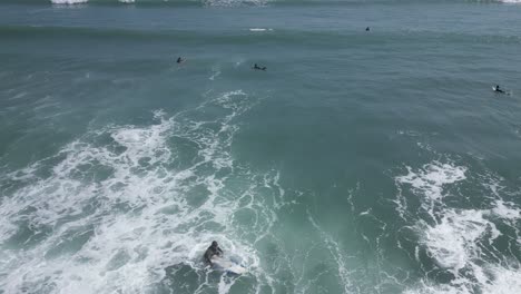 Aerial-spinning-shot-of-surfers-swimming-out-to