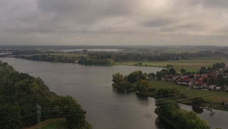 Drohnenaufnahme-Des-Sees-Mit-Dorf-Am-Flussufer