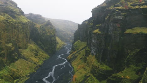Aerial-rise-above-river-running-though-rugged-misty