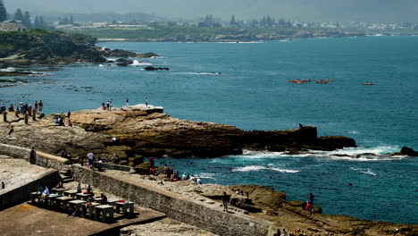 Tourists-on-rocky-coastline-whale-watching-and-kayakers