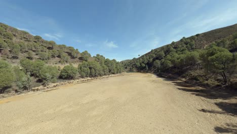 Low-aerial-flight-up-dry-gravel-river-bed