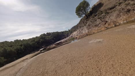 Fast-FPV-flight-along-dry-riverbed-to-old