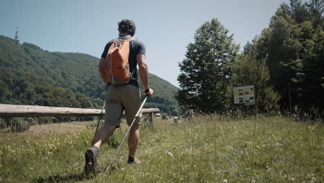 Man-with-backpack-walking-with-poles-towards-mountain-Bo?