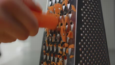 Man-shredding-a-carrot-with-a-grater-Cooking