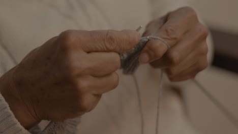 Close-up-slow-motion-shot-of-an-elderly-woman-using-knitting-hooks-to-make-a-square