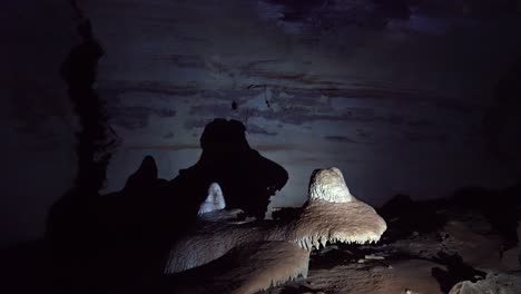 Handheld-shot-of-a-flashlight-lighting-up-a-cave-structure-creating-a-dinosaur-shadow-inside-the-famous-Lapa-Doce-cave-in-the-Chapada-Diamantina-National-Park-in-Bahia,-northeastern-Brazil