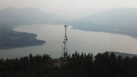 Aerial-view-of-radio-tower-on-top-of-mountain-with-lake-as-background