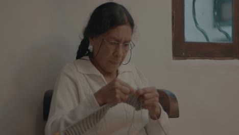 Slowmotion-shot-of-an-elderly-grandmother-knitting-the-pattern-into-a-scarf-at-home