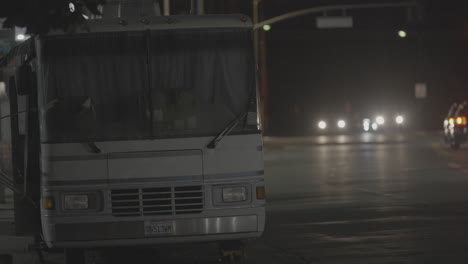 A-static-shot-of-a-white-bus-standing-on-a-vacant-road-at-night