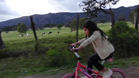 Pacing-shot-of-a-young-girl-cycling-down-a-country-road-in-Colombia