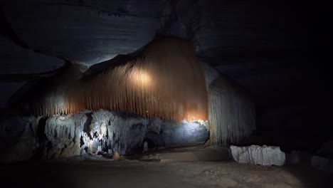 Handheld-shot-of-a-flashlight-lighting-up-a-huge-orange-and-white-cave-structure-inside-the-famous-Lapa-Doce-cave-in-the-Chapada-Diamantina-National-Park-in-Bahia,-northeastern-Brazil