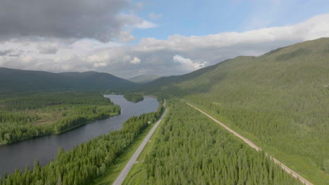 Drone-flyover-Scenic-Norwegian-landscape,-highway-by-the-Namsen-River-Surrounded-by-Lush-Spuce-forest