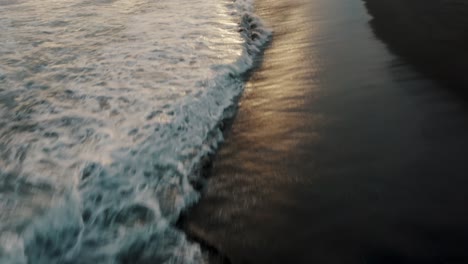 Foamy-Waves-Splashing-On-The-Black-Sand-Beach-Of-El-Paredon-In-Guatemala-At-Sunset---drone-shot