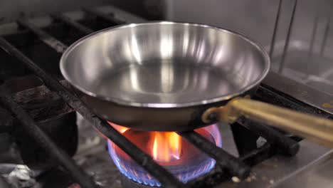 Unrecognizable-chef-putting-frying-pan-on-turned-on-gas-stove,-close-up