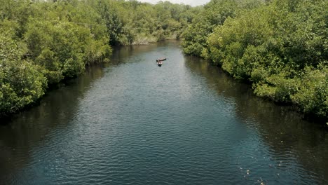 Holzboot-Zieht-Ein-Anderes-Boot-In-Einem-Ruhigen-Fluss-Mit-üppigen-Bäumen-In-Der-Nähe-Von-El-Paredon,-Guatemala