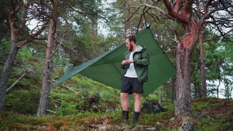 Man-With-Hammock-Camping-Shed-In-Wilderness