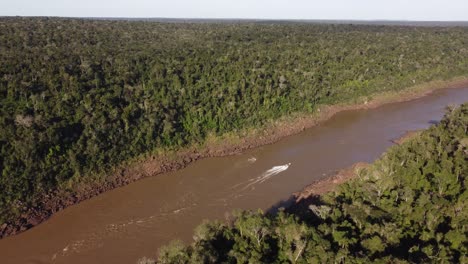 Aerial-following-shot-of-small-speedboat-cruising-on-amazon-river-along-Border-in-Brazil-and-Argentina