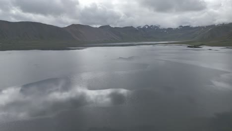 Vista-Aérea-Del-Lago-Tranquilo-Rodeado-Por-La-Cordillera-En-Islandia